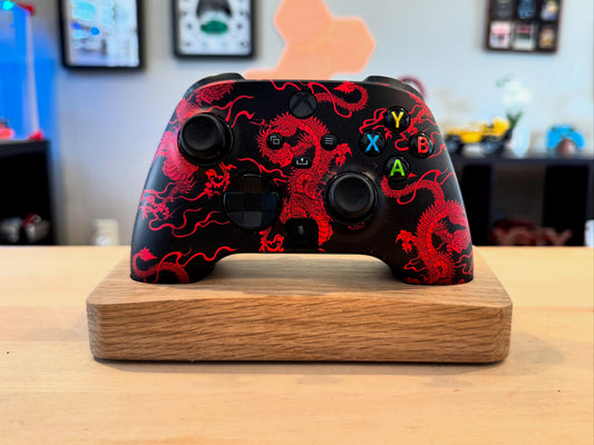 A Xbox Series X controller placed on an Oak wooden controller stand.